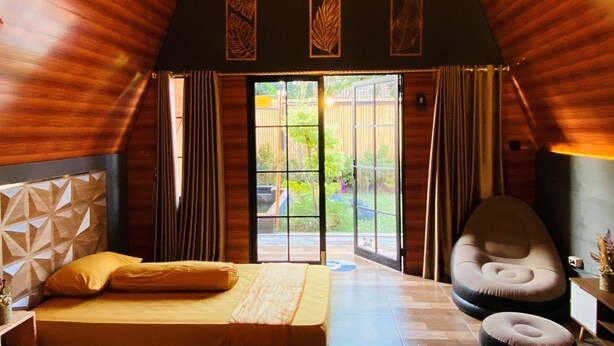 A cozy room with two beds, a sofa, and a large window. - Omah Abiza (Depok)