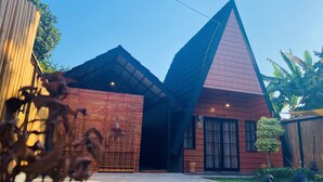 A modern building with a triangular roof and a wooden facade. - Omah Abiza (Depok)