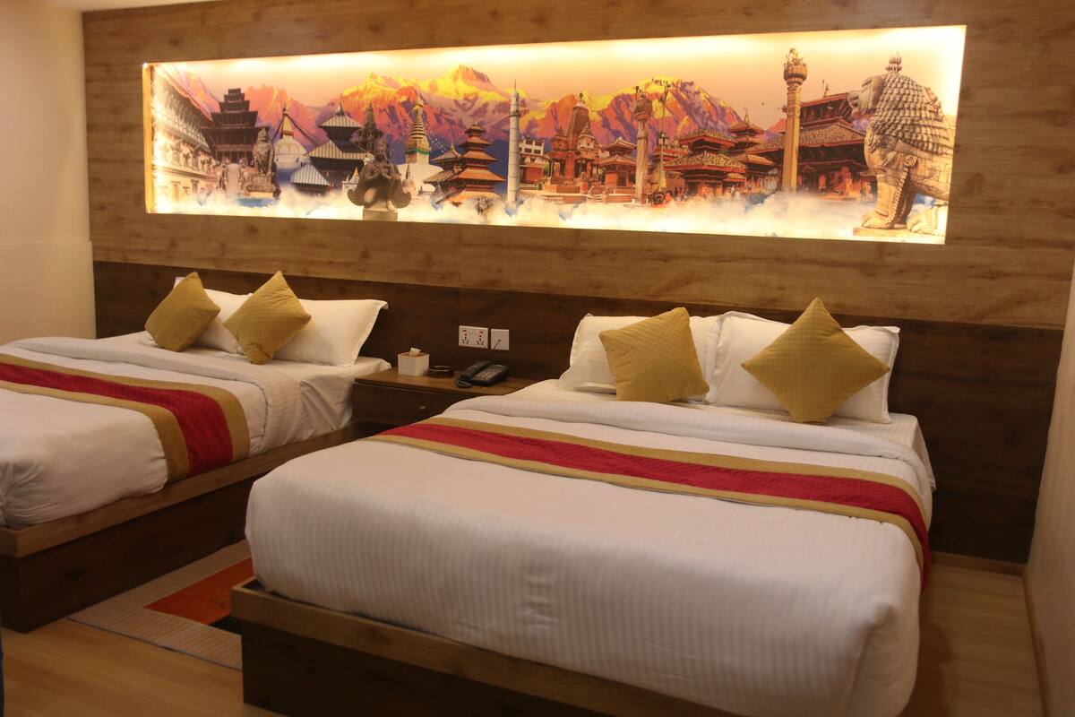 A hotel room with two beds, each with white bedding and red and yellow striped bed runners. A large wall-mounted artwork depicting a traditional Asian scene is above the beds.