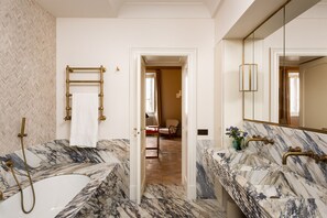 A bathroom with marble countertops, a bathtub, and a shower with brass fixtures. - Idyllia | Casa Mina Luxury (Roma)