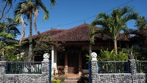 Uma casa com telhado de telhas, parede de pedra e portão azul.
