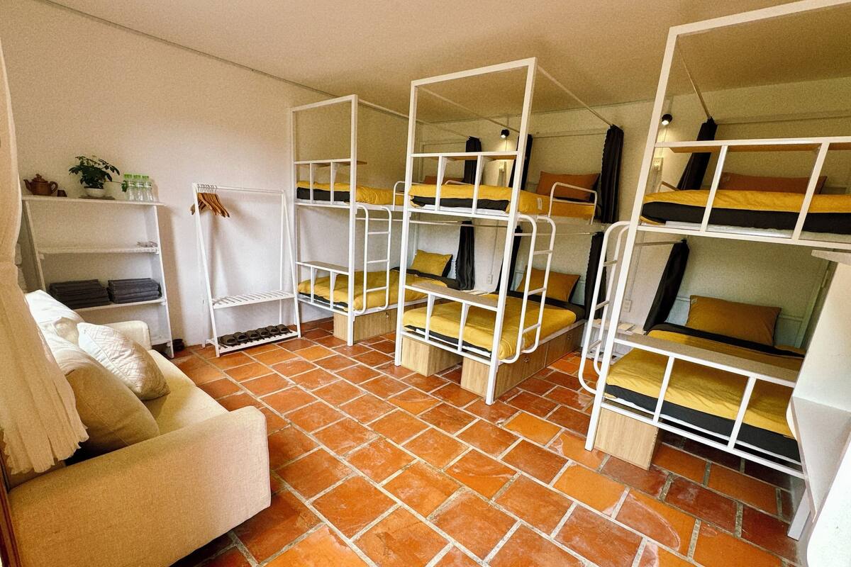 A dormitory room with bunk beds, a sofa, and a tiled floor.