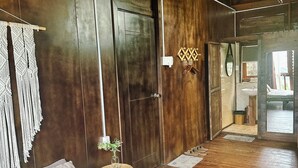 A wooden room with a bed, a door, and a hallway leading to a bathroom. - Dalat Zen Homestay (3 Bao Loc)