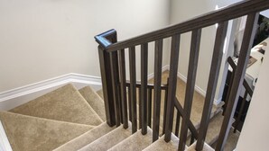 A staircase with a beige carpet, a dark wooden handrail, and a wall-mounted painting of abstract flowers. - Spacious and Cozy Room with Private Bathroom in a house with WiFi, AC in Ottawa. (Ottawa)
