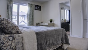 A bedroom with a bed, a desk, a chair, a potted plant, and a window with curtains. - Spacious and Cozy Room with Private Bathroom in a house with WiFi, AC in Ottawa. (Ottawa)