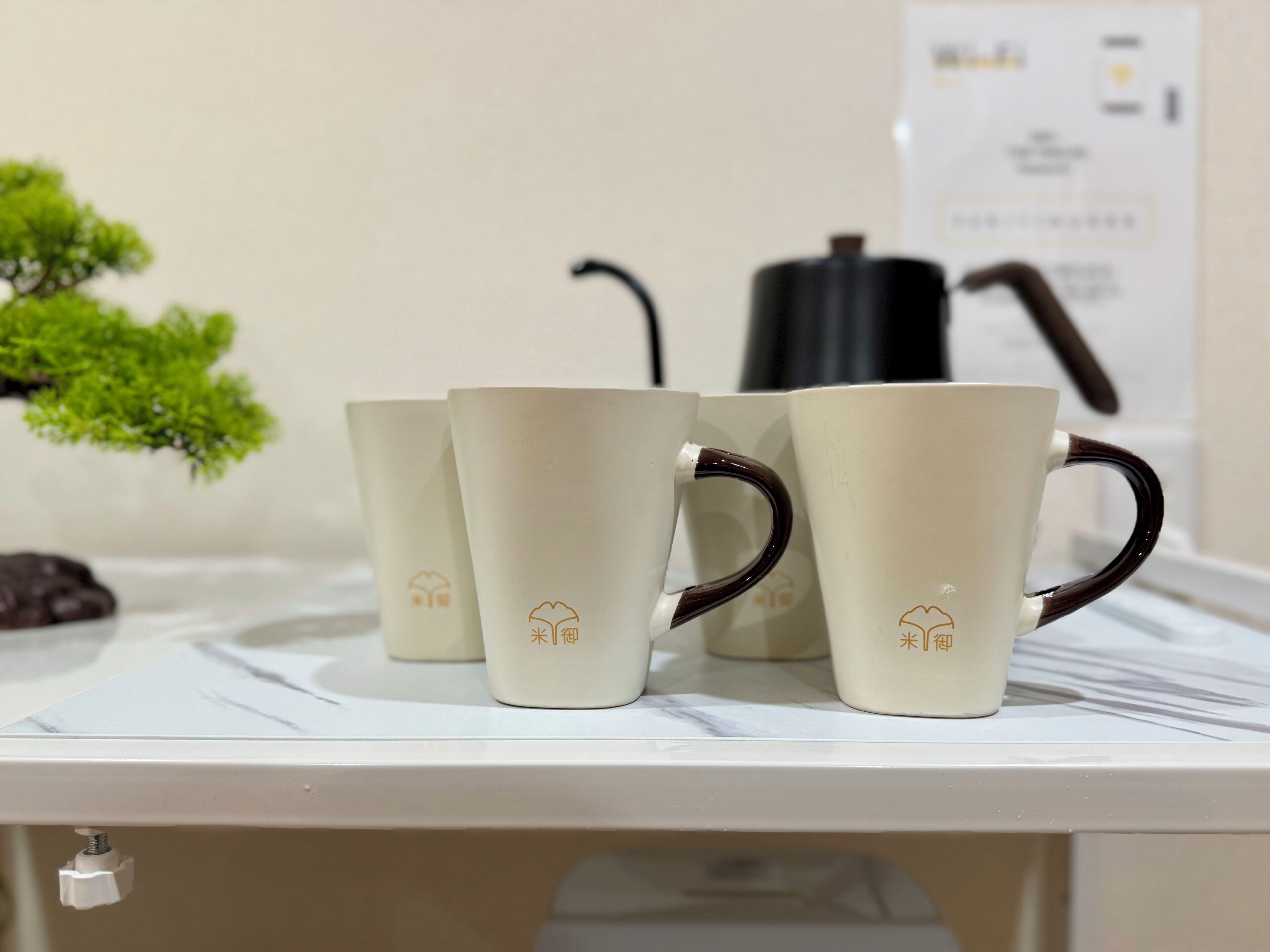 Three white ceramic mugs with brown handles on a white marble countertop.