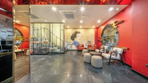 A modern lobby with a red wall, a mural, and a seating area with ottomans and chairs. - U Tor Yaowarat (Bangkok)