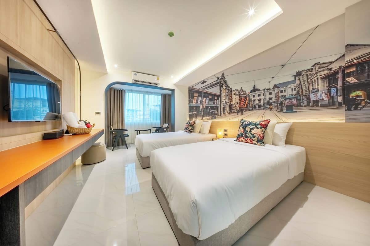 A modern hotel room with two beds, a desk, a chair, and a large window.