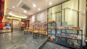 A modern interior with a marble floor, wooden chairs, a snack bar, and a mural of a cityscape. - U Tor Yaowarat (Bangkok)