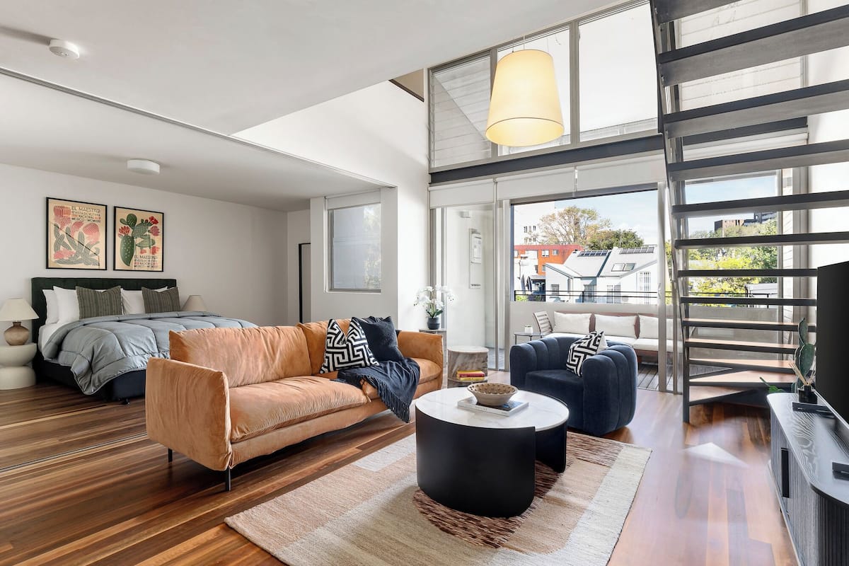 Un salon moderne avec un canapé, une table basse et un escalier menant à un niveau supérieur.