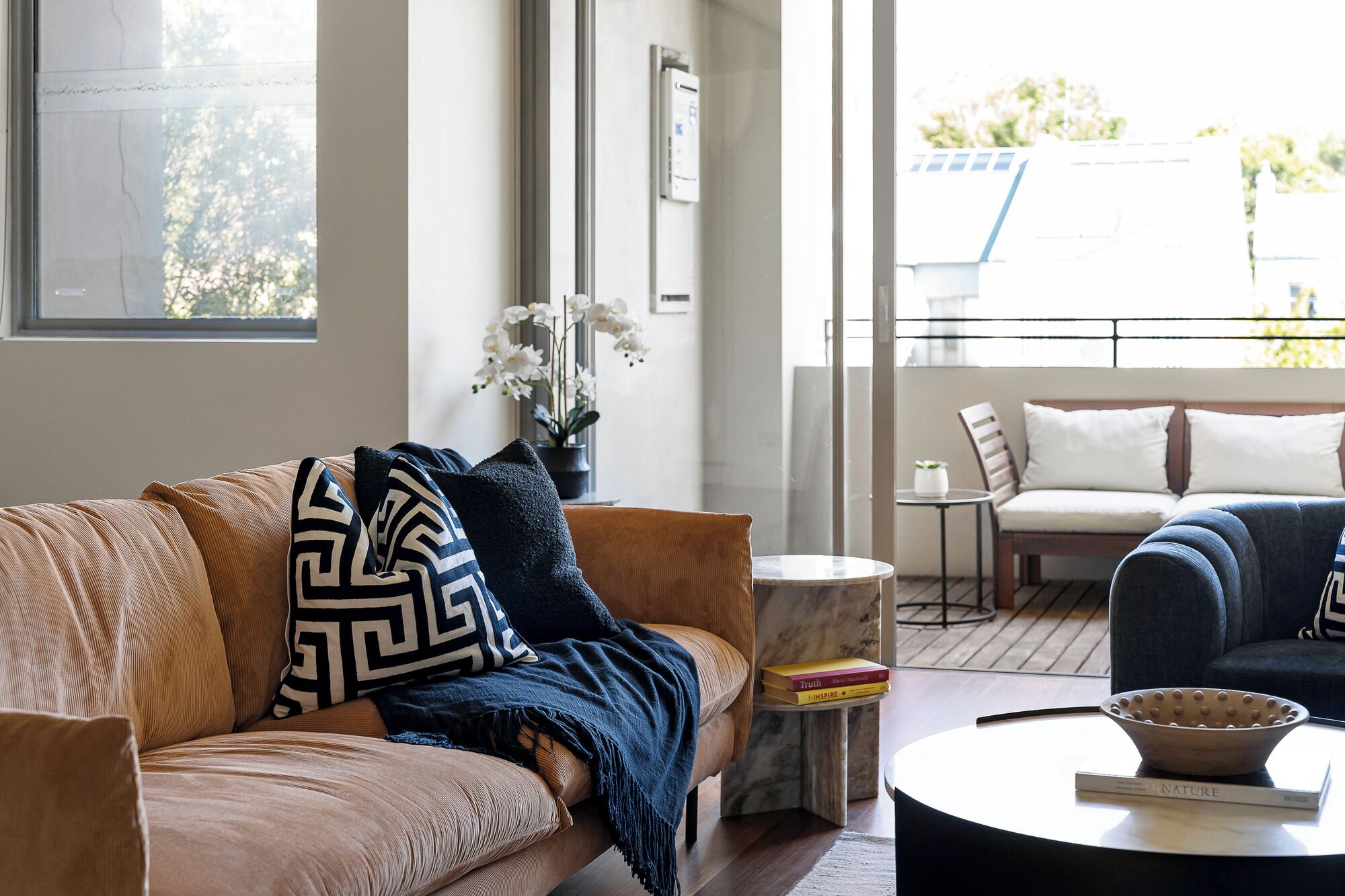 A modern living room with a sofa, a coffee table, and a view of the outdoors.