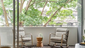 A balcony with two rocking chairs, a potted plant, and a wooden floor.