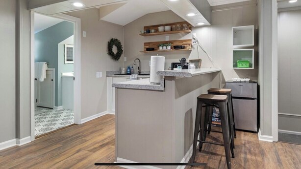 Una cocina moderna con una isla central, estantes de madera y un refrigerador.