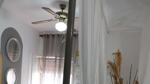 Un dormitorio con una cama, un ventilador de techo, una mesita de noche y un atril.