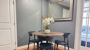 A dining area with a round wooden table, four black chairs, and a potted orchid arrangement. - Downtown Atlanta Condo with City Views (Atlanta)