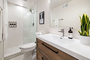 Un baño moderno con ducha, inodoro y tocador.