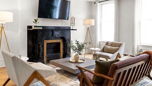 A modern living room with a fireplace, comfortable seating, and a flat-screen TV. - Sleeps 12, Mxn Streets (Pittsburgh)