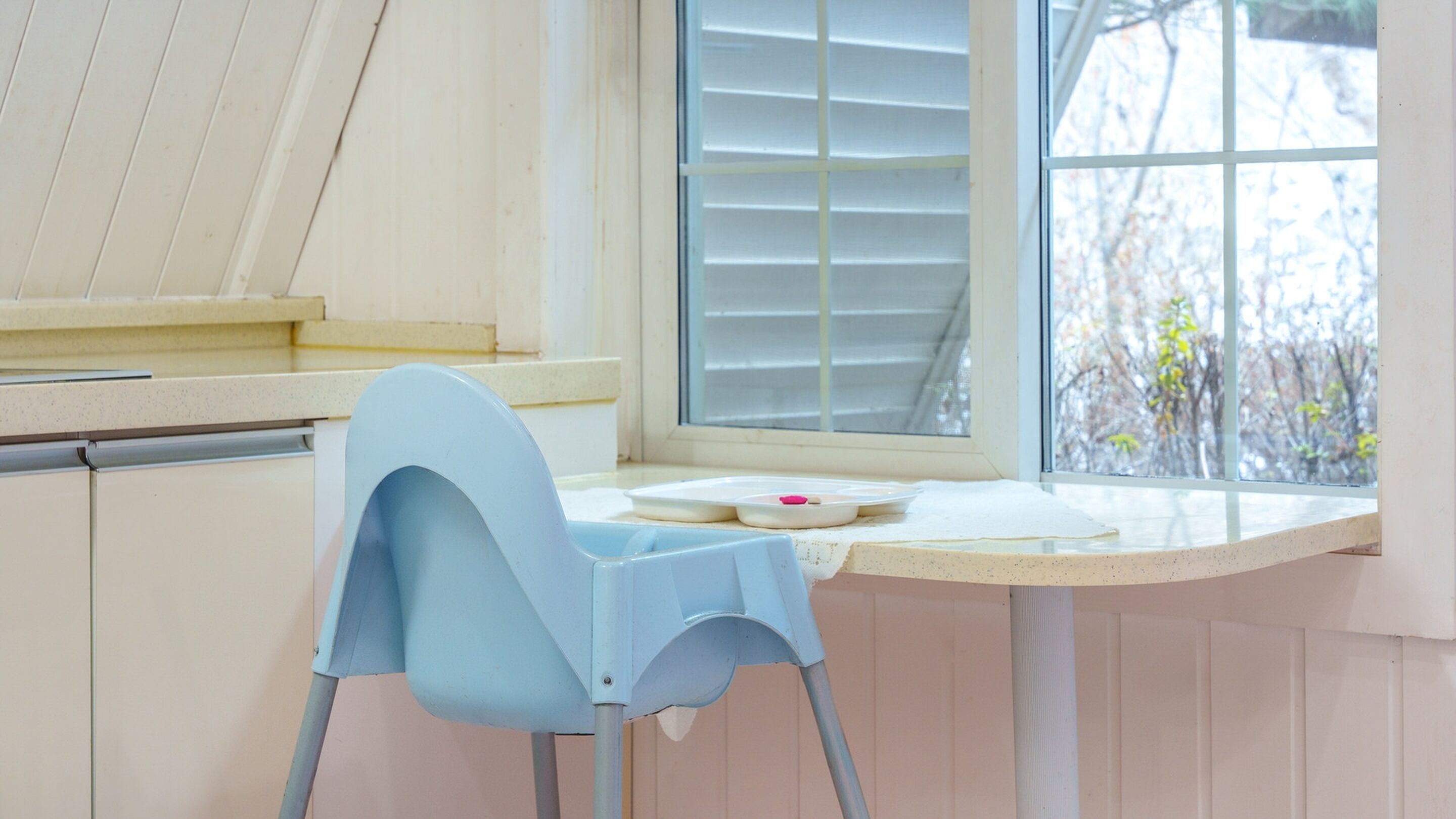 Ein Zimmer mit Fenster, einem Sessel und einem Tisch mit Teller und Tasse.