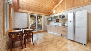 A wooden-paneled kitchen with a dining area, a refrigerator, and a microwave. - Gapyeong Lulu Kids Pension (Gapyeong)