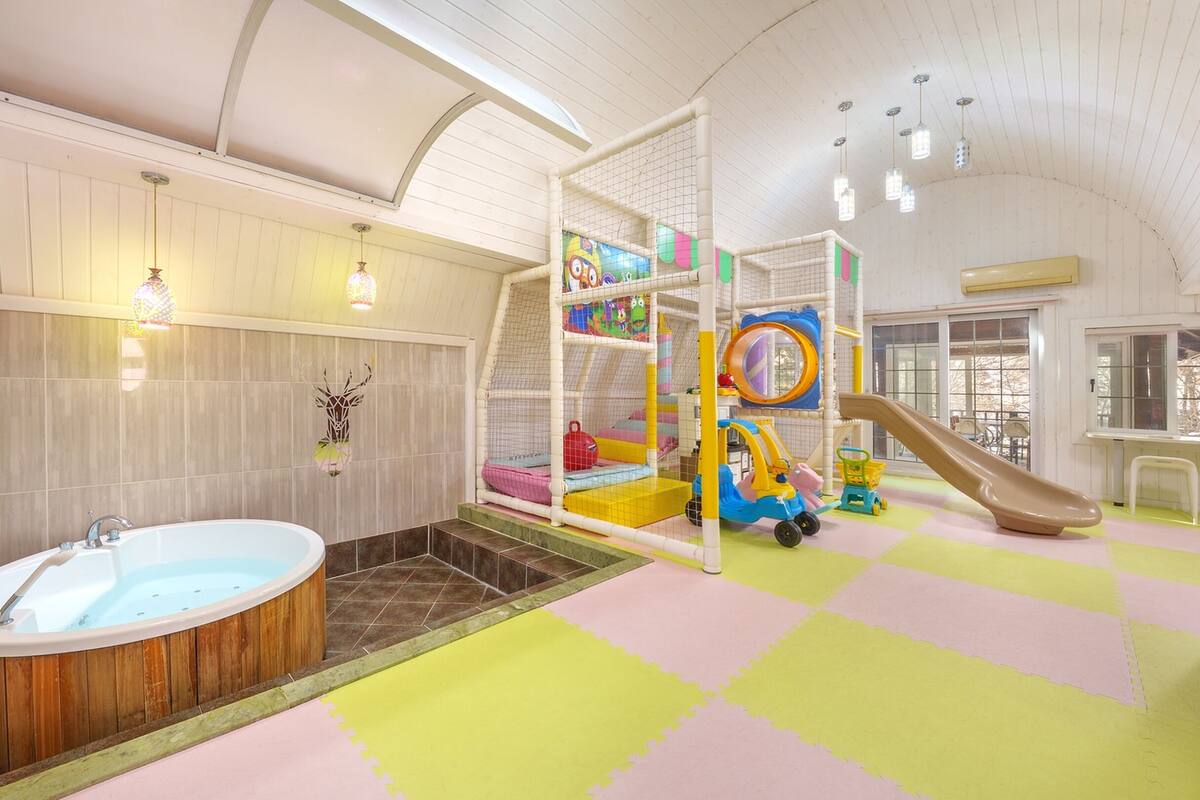 Ein Spielbereich für Kinder mit Rutsche, Kletternetz und Whirlpool.