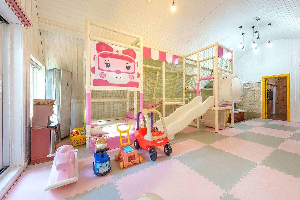 Ein Kinderspielbereich mit Rutsche, Spielgeräten und Spielzeug.