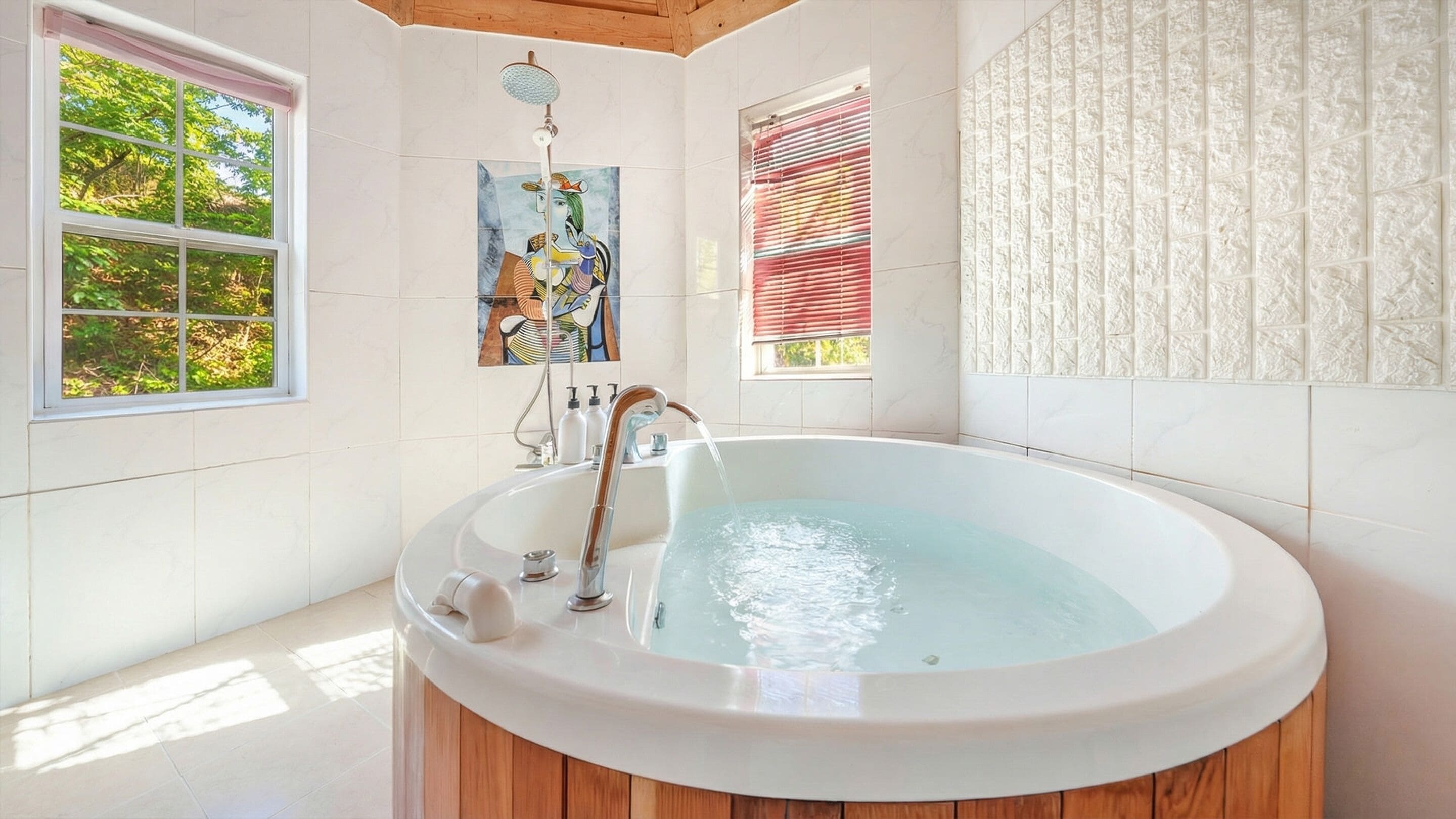 A modern bathroom with a freestanding bathtub, large windows, and a view of greenery.