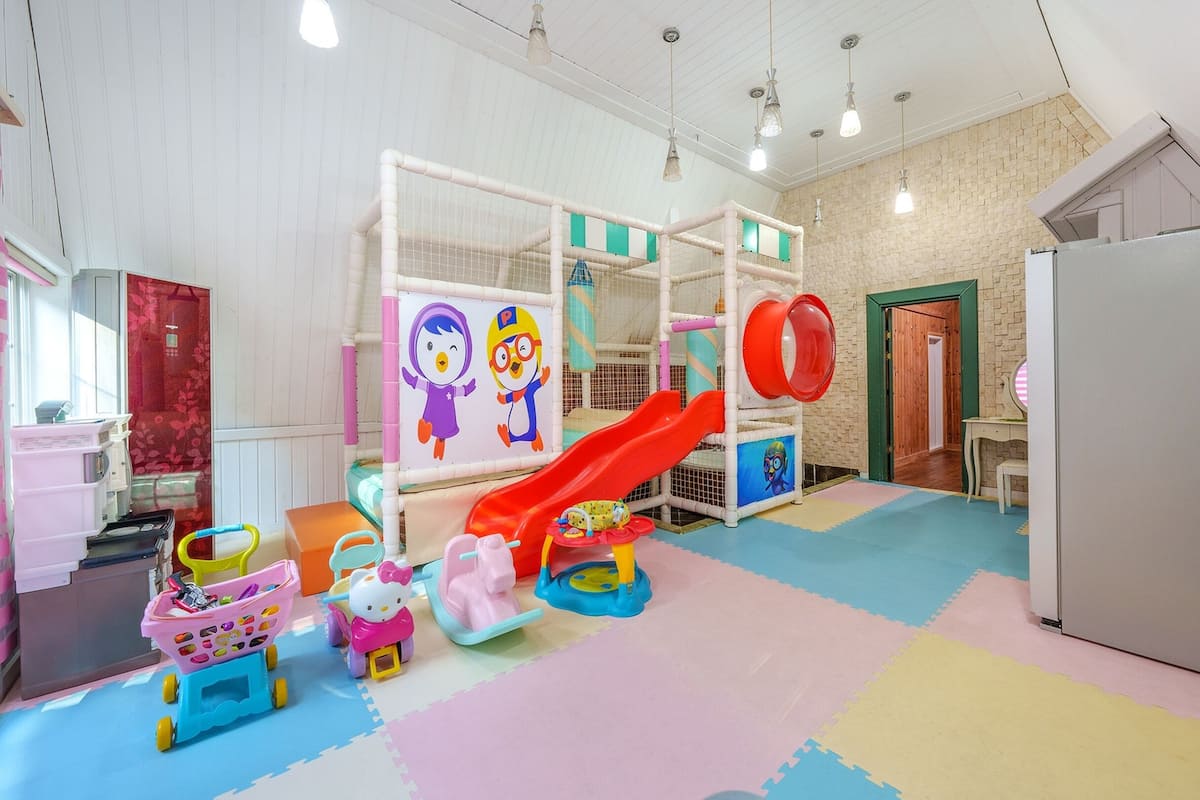 Ein Kinderspielbereich mit Rutsche, Spielzeug und einem Spielstall.