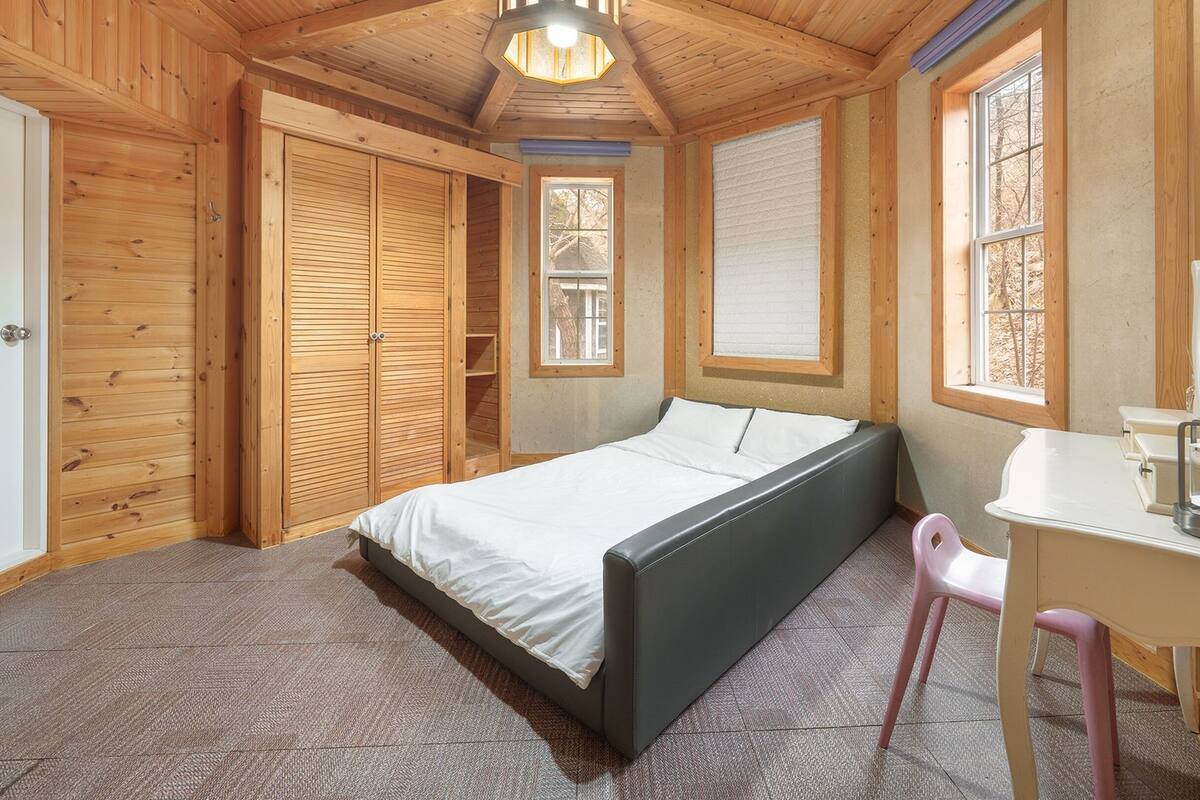 Ein Schlafzimmer mit Bett, Schreibtisch, Stuhl und Kleiderschrank.