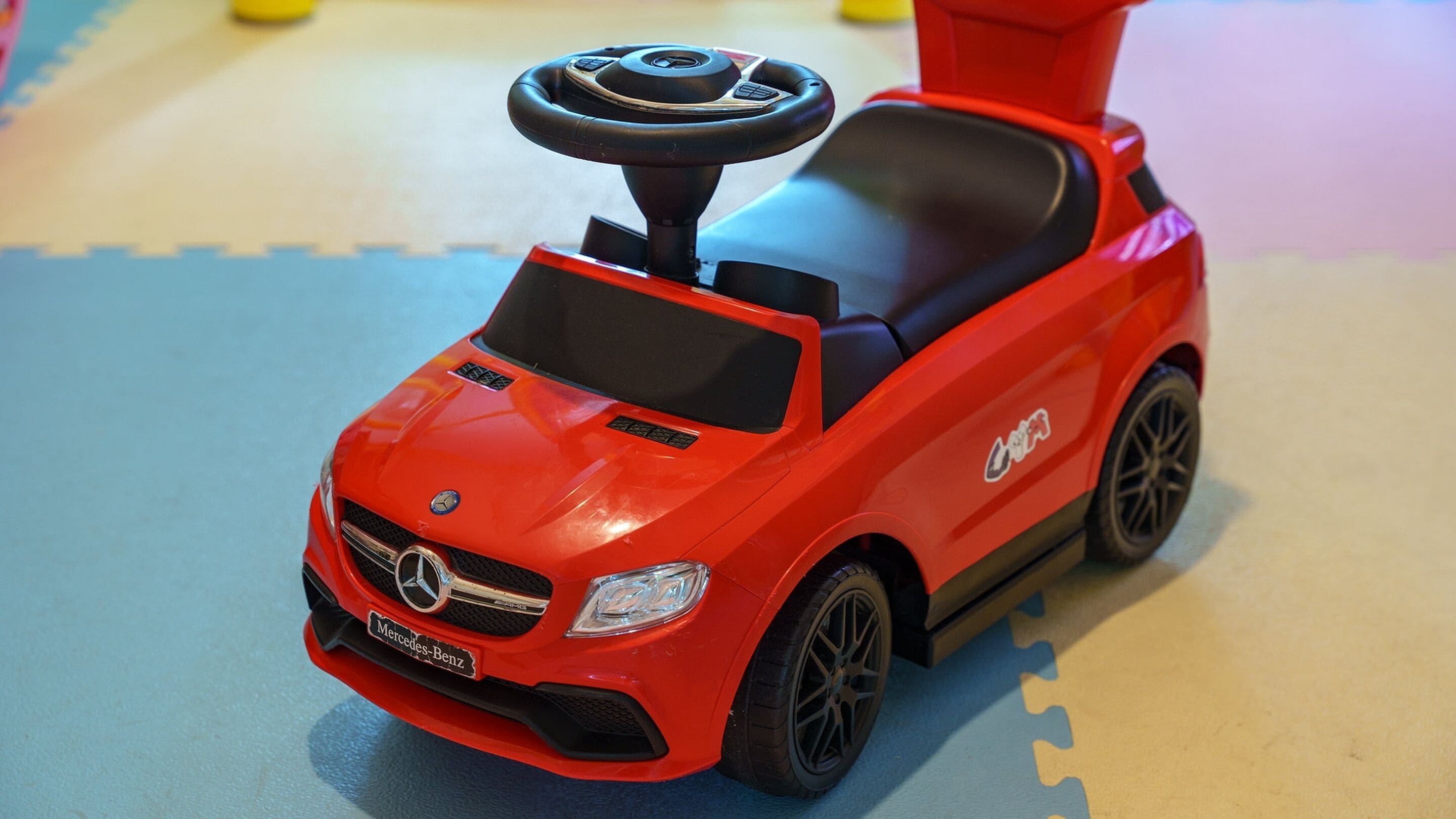 Un coche de juguete rojo con volante y asiento negro.