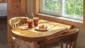 A wooden table with two iced drinks and a plate of croissants by a window with a view of greenery. - Gapyeong Lulu Kids Pension (Gapyeong)