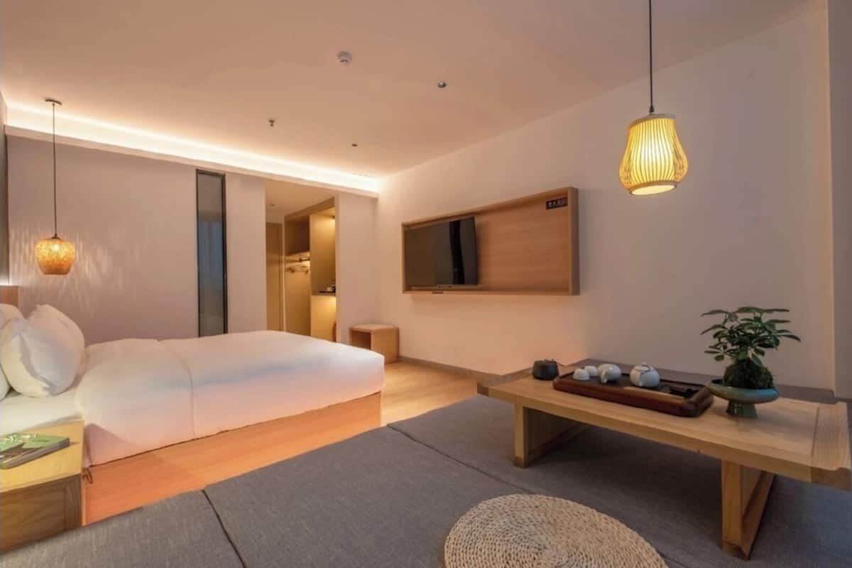 Una habitación de hotel moderna con una cama grande, una mesita de noche y un televisor montado en la pared.