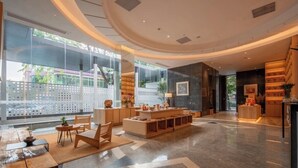 A spacious lobby with a central seating area, a reception desk, and a view of the outside through large windows. - SHIJING HOTEL (Guangzhou)