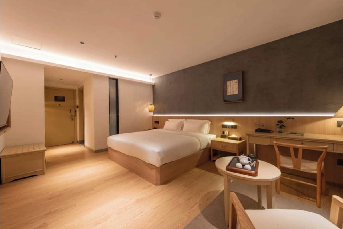 Una habitación de hotel moderna con una cama grande, mesitas de noche, un escritorio y una silla.