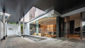 A modern hotel interior with a glass facade, a central seating area, and a visible staircase. - SHIJING HOTEL (Guangzhou)