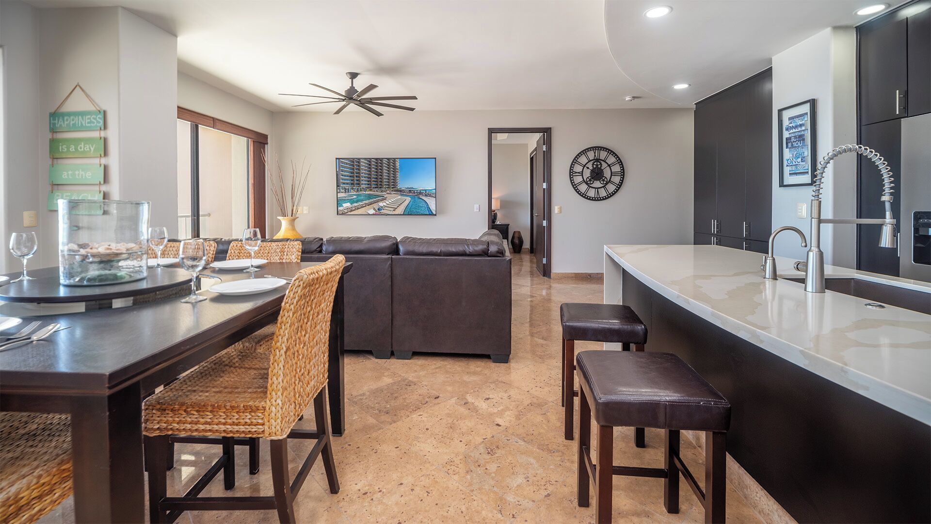 A modern kitchen with a dining area, a large island with a sink, and a seating area with a sofa and chairs.