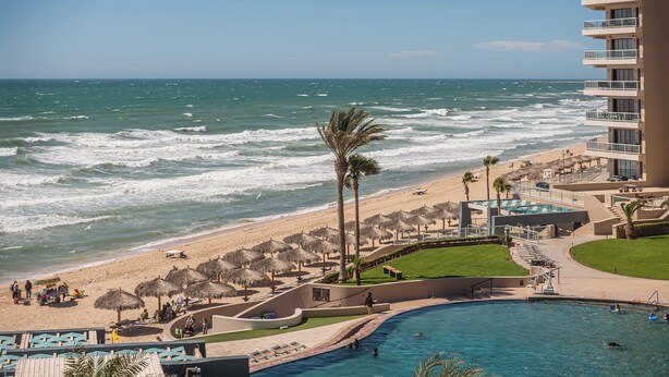 A resort with a pool, beach, and ocean view.