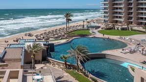 A resort with a large pool, beach area, and ocean view.