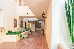 A narrow corridor with tiled flooring, potted plants, and a cactus on the right. - GuestHost - Luxury Apt in Porto Cervo square with parking (Porto Cervo)