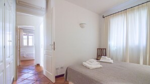 Una habitación de hotel con cama, mesita de noche, lámpara y vistas al exterior.