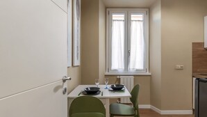 A compact kitchen with a dining table, two chairs, and a window with curtains.