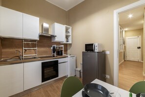 A compact kitchen with white cabinets, a microwave, a refrigerator, and a sink.