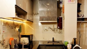 Una cucina compatta con piani di lavoro scuri, forno integrato e frigorifero.