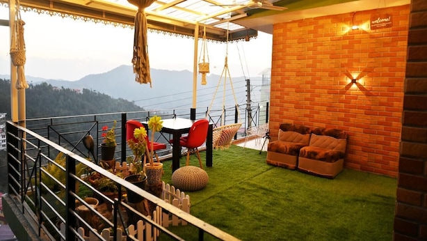 Un balcone con tavolo, sedie e divano, affacciato su un paesaggio montuoso.