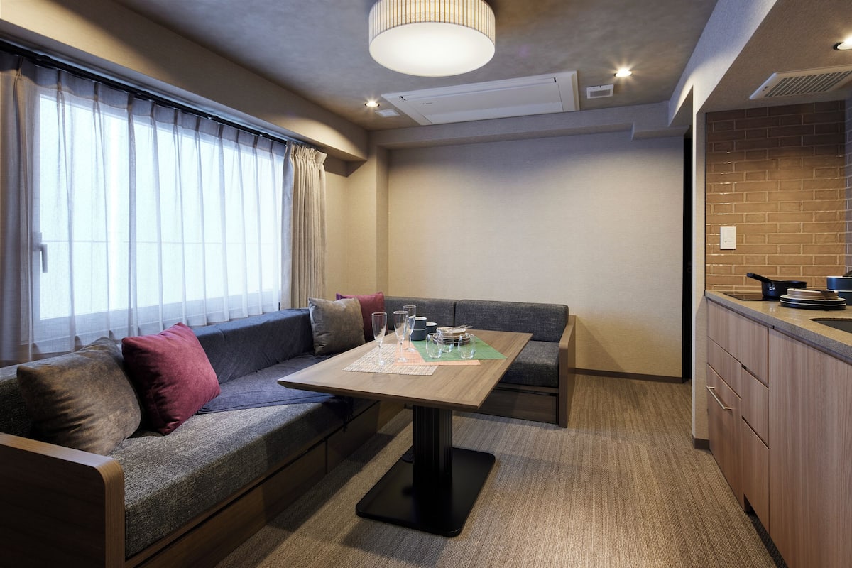 Een compacte woonruimte met een bank, een eettafel en een kitchenette.