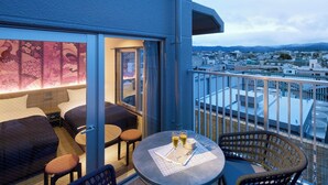 A balcony with a seating area, a table with glasses, and a view of the cityscape.