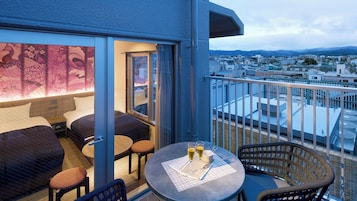 A balcony with a seating area, a table with glasses, and a view of the cityscape.