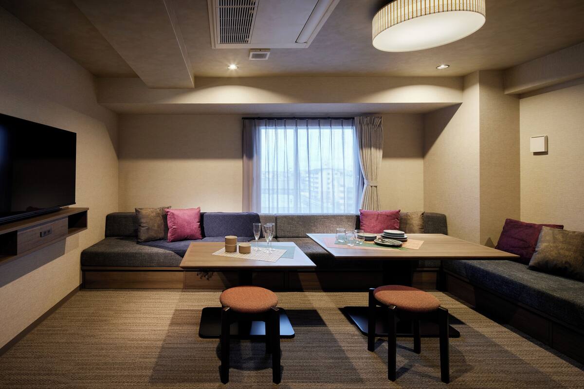 Een moderne woonkamer met een bank, twee stoelen, een eettafel en een flatscreen televisie.
