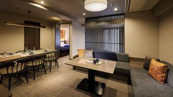 Een moderne hotelkamer met een zithoek, een bank en een groot raam met zonwering.