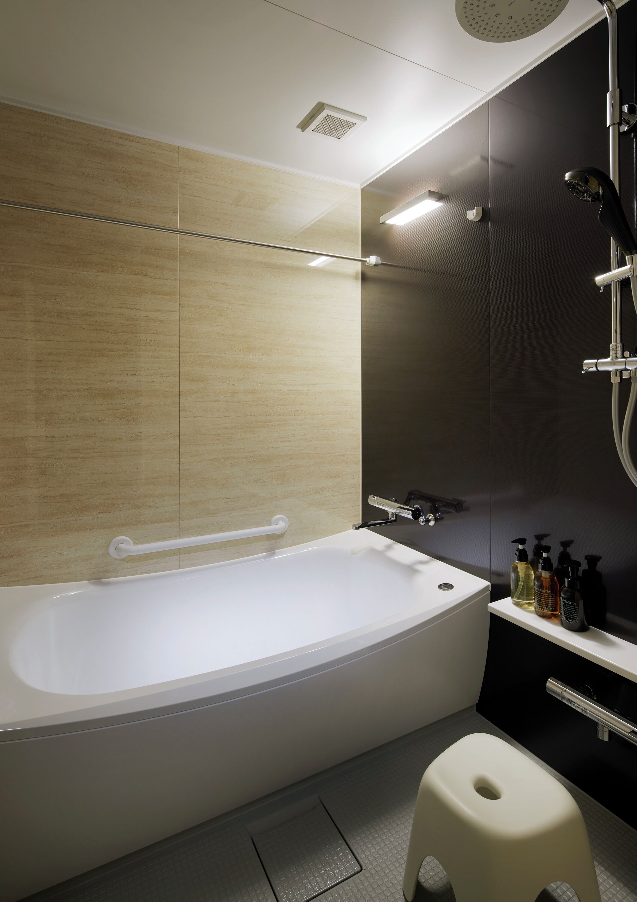 A modern bathroom with a freestanding bathtub, a showerhead, and a small stool.