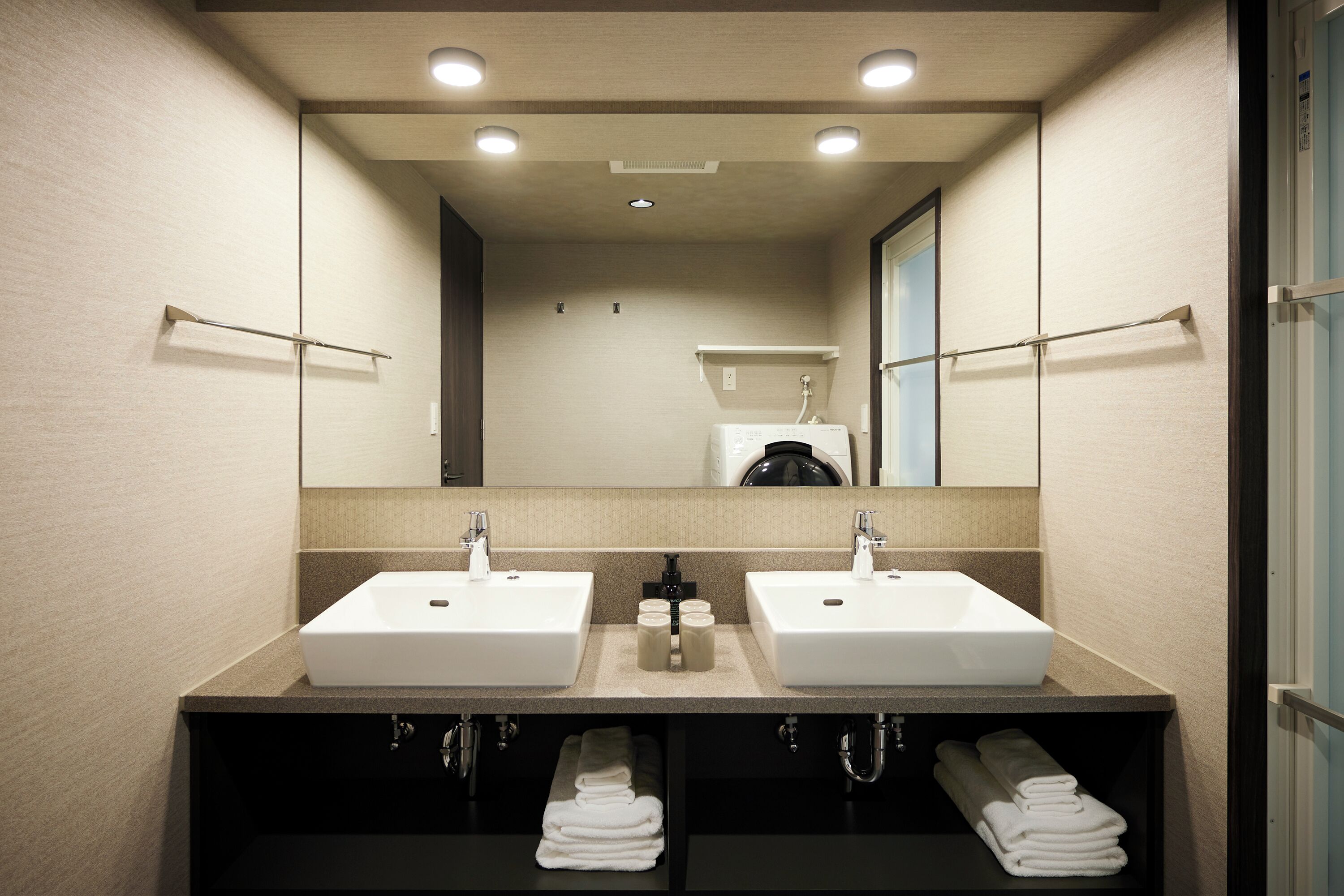 A bathroom with two sinks, a mirror, and a towel rack.